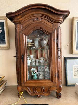 une armoire en bois avec une porte vitrée, dans un coin de la pièce