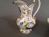 a white and gold vase with flowers on it next to a plate