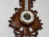 une horloge en bois accrochée au mur, sur laquelle se trouve un thermomètre