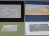 trois tableaux posés sur une table, avec une photo de montagnes en arrière-plan