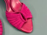 une paire de chaussures à talons hauts roses posées sur une surface grise