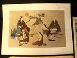 two asian paintings on display on a table next to a piece of paper
