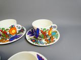 trois tasses et soucoupes ornées de motifs colorés, posées sur une table