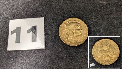 un gros plan sur deux pièces d'or posées sur une table, à côté d'une feuille de papier