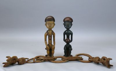 paire de figurines en bois représentant deux hommes et un chien sur une branche