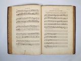 an open book with music notes on it sitting on a table