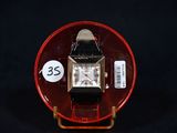 a watch on a red plate with a price tag on it