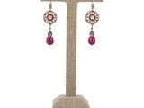 a pair of earrings with pink beads on a stand