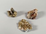 three pieces of gold and a piece of silver on a white surface