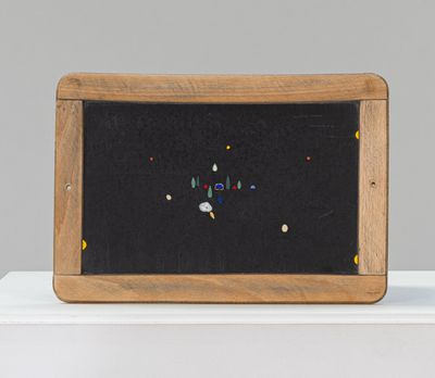 un petit tableau noir orné de perles colorées, posé sur une table