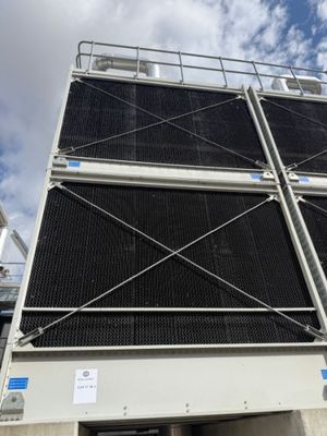 an industrial cooling unit with a sky background and clouds in the background