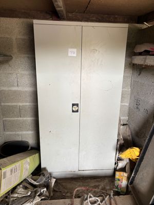 un réfrigérateur blanc dans une pièce sale, avec des outils par terre