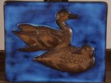 two ducks that are sitting on a blue tile