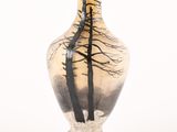 un vase en verre orné d'une peinture représentant des arbres
