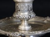 a silver candle holder on a silver plate on a black background