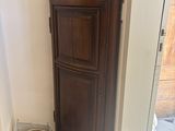 a wooden cabinet in the corner of a bathroom