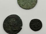 three roman coins and a roman coin on a white surface