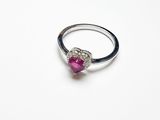 une image représentant une bague en pierre rose posée sur une surface blanche