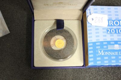 une boîte posée par terre, contenant une pièce de monnaie