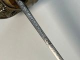 a metal object with a handle on a white surface