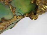 a green vase with a gold decoration on it