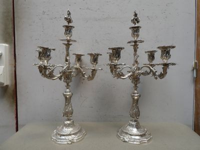 deux chandeliers en argent posés l'un à côté de l'autre sur une table