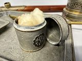 a metal tray with a silver cup and a spoon on it