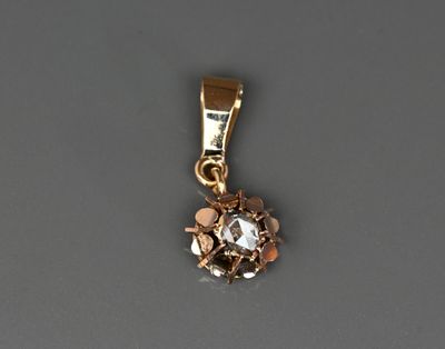 un gros plan d'un pendentif plaqué or orné d'un diamant blanc