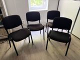 quatre chaises noires dans une pièce avec une fenêtre à l'arrière-plan