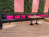 un canapé noir avec des coussins roses et une table en bois