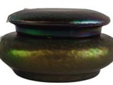 a green vase with a lid sitting on a white surface
