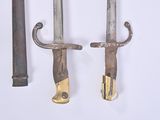 two old knives hanging on a wall next to a hammer