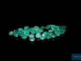a close up of a bunch of green gems on a black surface