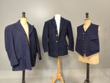 trois mannequins vêtus de vestes et de gilets, exposés devant un mur gris