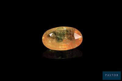 a yellow sapphire stone on a black surface