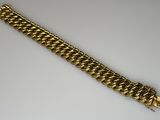 a close up of a gold chain bracelet on a white surface
