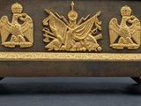 brass figurines of angels and demons on a bench with a black background