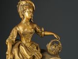a gold statue of a woman with a basket on her lap