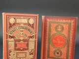 three small books are lined up on a black surface