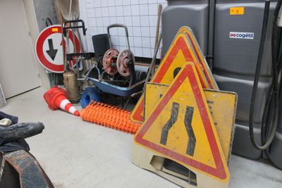 un panneau jaune et rouge posé par terre à côté d'une pile de cônes orange