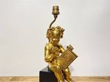 an image of a gold statue of a child holding a book