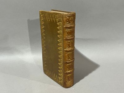 un vieux livre posé sur une table blanche à côté d'un mur blanc