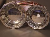 two silver plates sitting on top of each other on a table