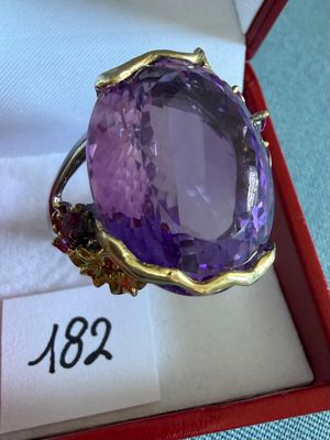 une photo d'une bague en pierre violette dans un écrin rouge