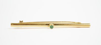 yellow gold tie bar with a green stone in the middle