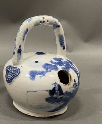 a blue and white vase with a handle on a table