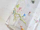 a clear glass vase with colorful flowers and insects on it