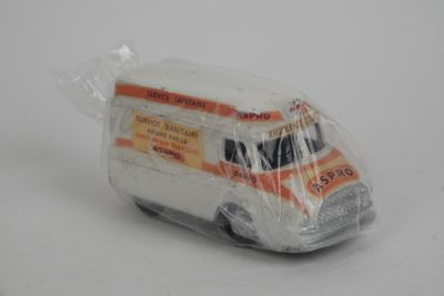 une petite camionnette miniature emballée dans du plastique, posée sur une surface blanche