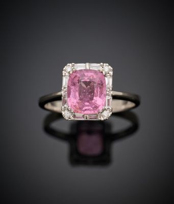 une bague sertie d'un saphir rose et de diamants, posée sur un fond noir