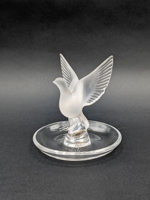 a clear glass bird figurine sitting on top of a glass plate
